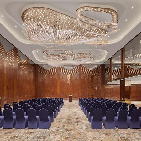 Ramses Hilton Hotel & Casino Kairo Exteriör bild The photo shows a large, elegantly designed interior space, likely a conference or event room. The walls feature rich, dark wood, and the ceiling is adorned with an intricate lighting design, creating a sophisticated ambiance. Rows of blue chairs are