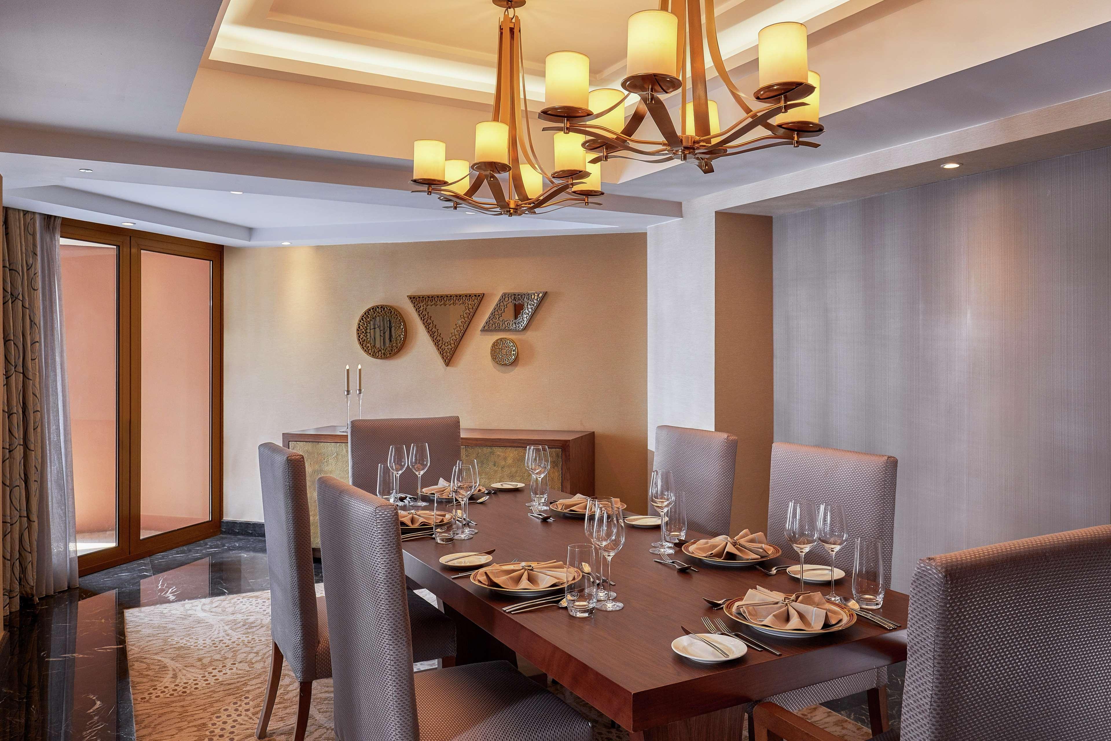 Ramses Hilton Hotel & Casino Kairo Exteriör bild The photo shows a sophisticated dining room setup. There is a large wooden dining table centered in the room, surrounded by upholstered chairs. The table is elegantly set with plates, glasses, and folded napkins, indicating a formal dining arrangemen