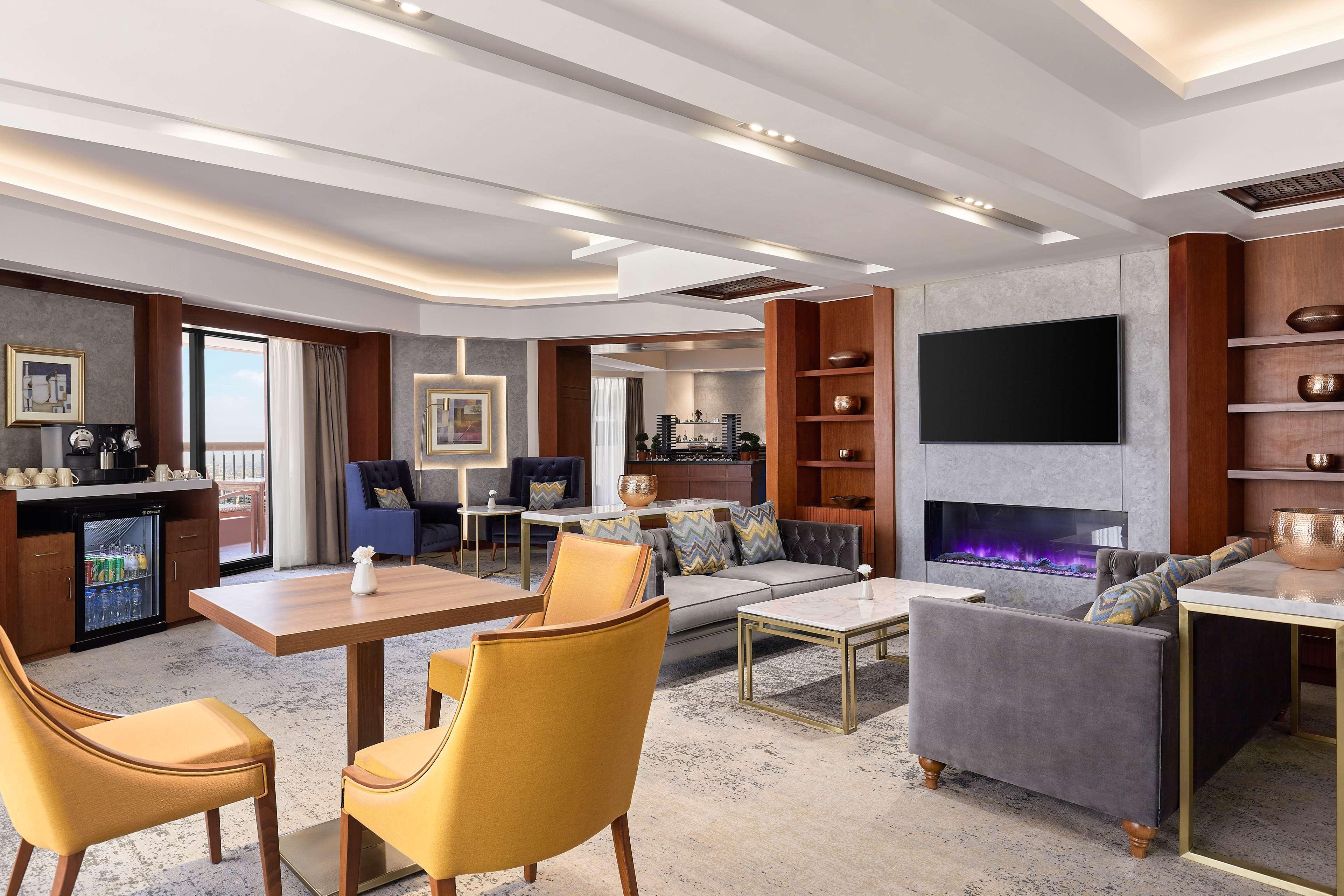 Ramses Hilton Hotel & Casino Kairo Exteriör bild The photo shows a modern and stylish living space or lounge area. It features a combination of comfortable seating, including a gray sofa and yellow chairs. A small wooden table is positioned in the center of the seating arrangement. In the backgroun
