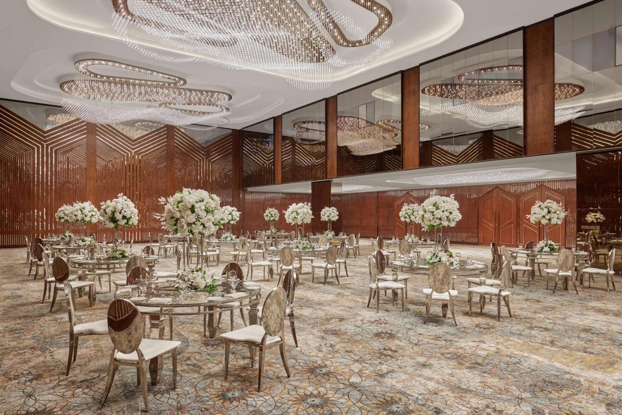 Ramses Hilton Hotel & Casino Kairo Exteriör bild The photo shows an elegantly designed banquet room or event space. The ceiling features intricate chandeliers that provide ambient lighting. The room is adorned with large mirrors that enhance its spaciousness. 

Tables are arranged throughout the sp
