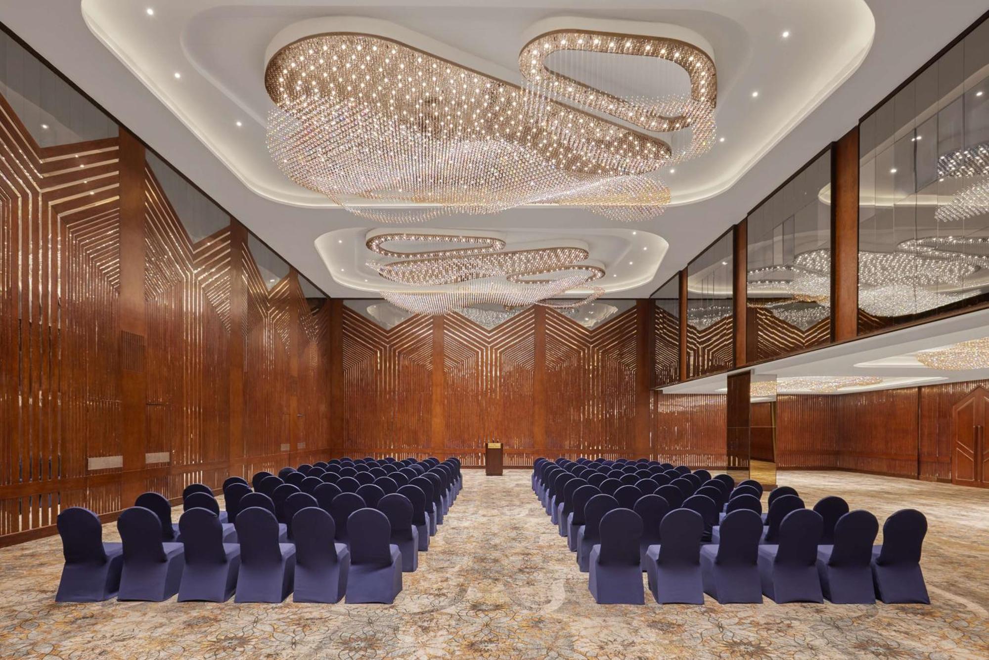 Ramses Hilton Hotel & Casino Kairo Exteriör bild The photo shows a large, elegantly designed interior space, likely a conference or event room. The walls feature rich, dark wood, and the ceiling is adorned with an intricate lighting design, creating a sophisticated ambiance. Rows of blue chairs are